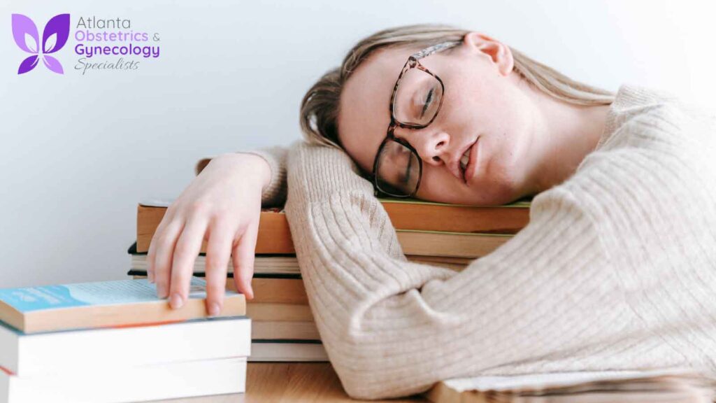 A woman resting her head on a pile of books and visibly distressed.