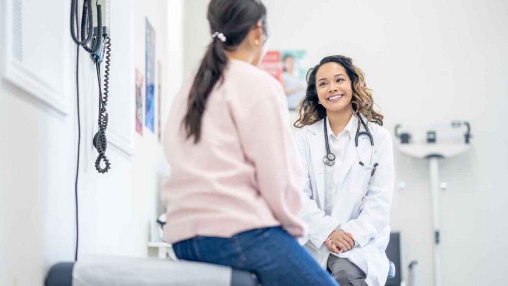 A doctor discussing with a patient inside an assessment room.