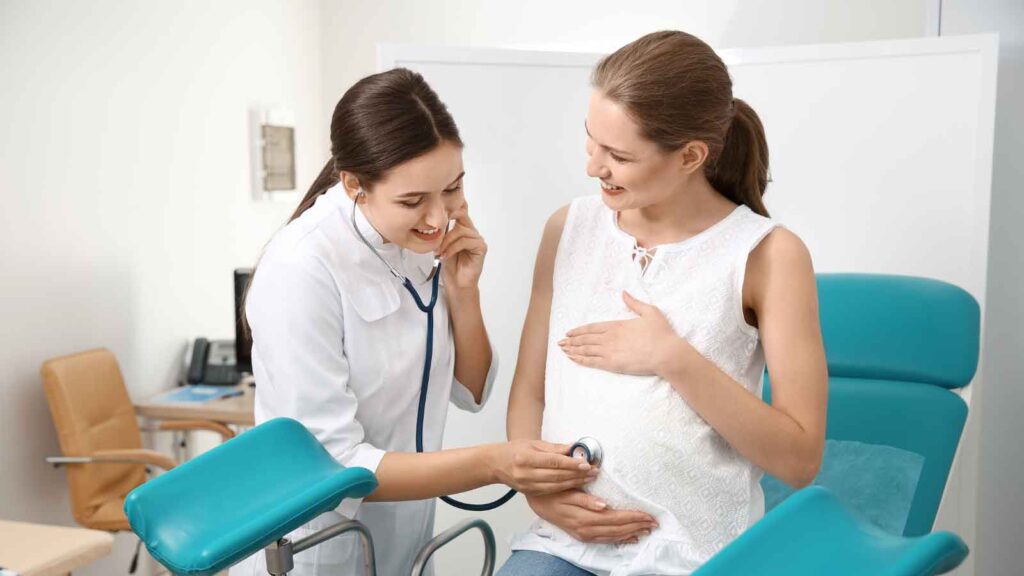  A pregnant woman undergoing a check-up by an OBGYN in a clinical setting.
