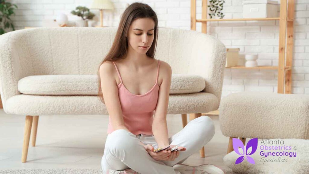 Woman on the floor staring at a few pills in her hand