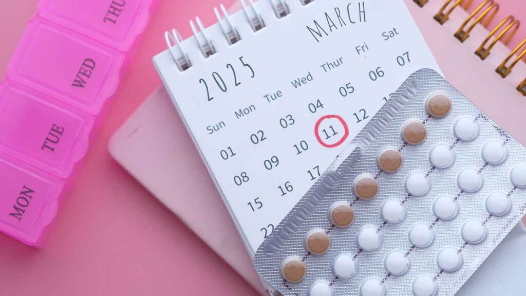 Calendar on a table beside a pack of birth control pills