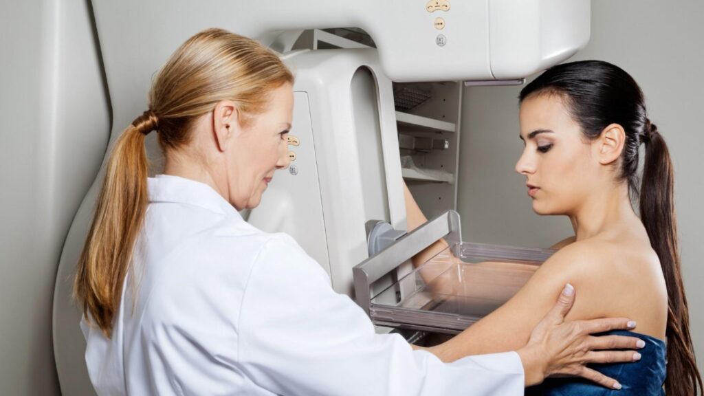 Woman undergoing mammography with assistance from a medical professional