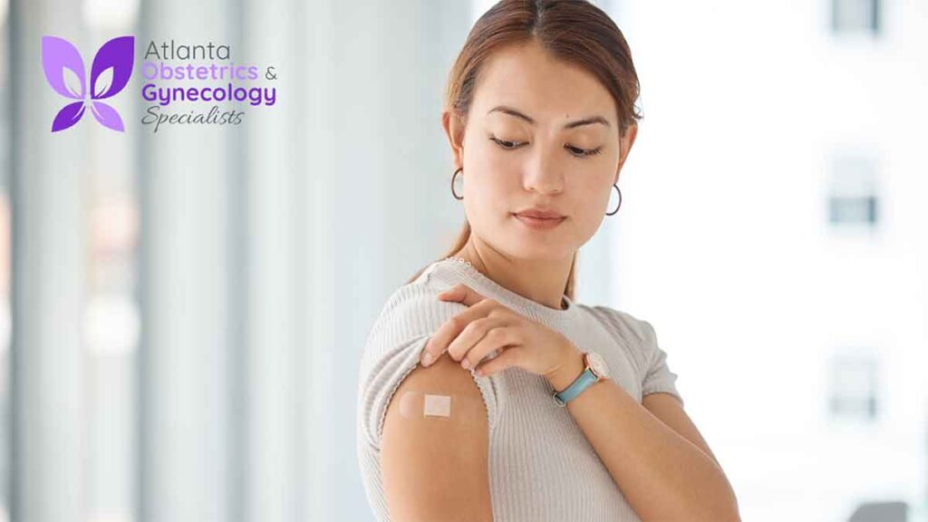 Woman gently holding her arm and looking at the injection site after receiving a vaccine
