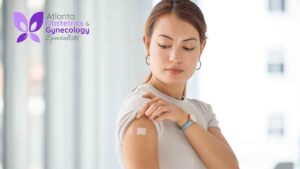 Woman gently holding her arm and looking at the injection site after receiving a vaccine