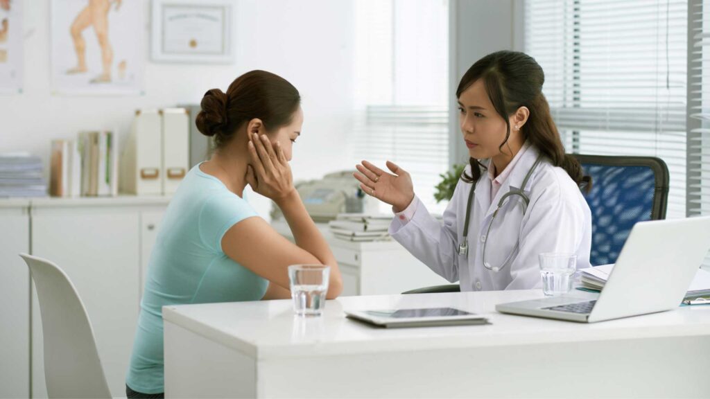 Female patient seated in a medical office, attentively listening to her obstetrician-gynecologist