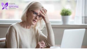 A mid-aged woman sitting in front of her laptop with a confused expression