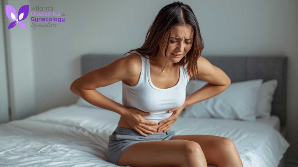 A woman showing signs of severe abdominal discomfort, clutching her stomach while sitting on a bed.