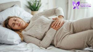 Woman resting on her side while experiencing lower abdominal pain.